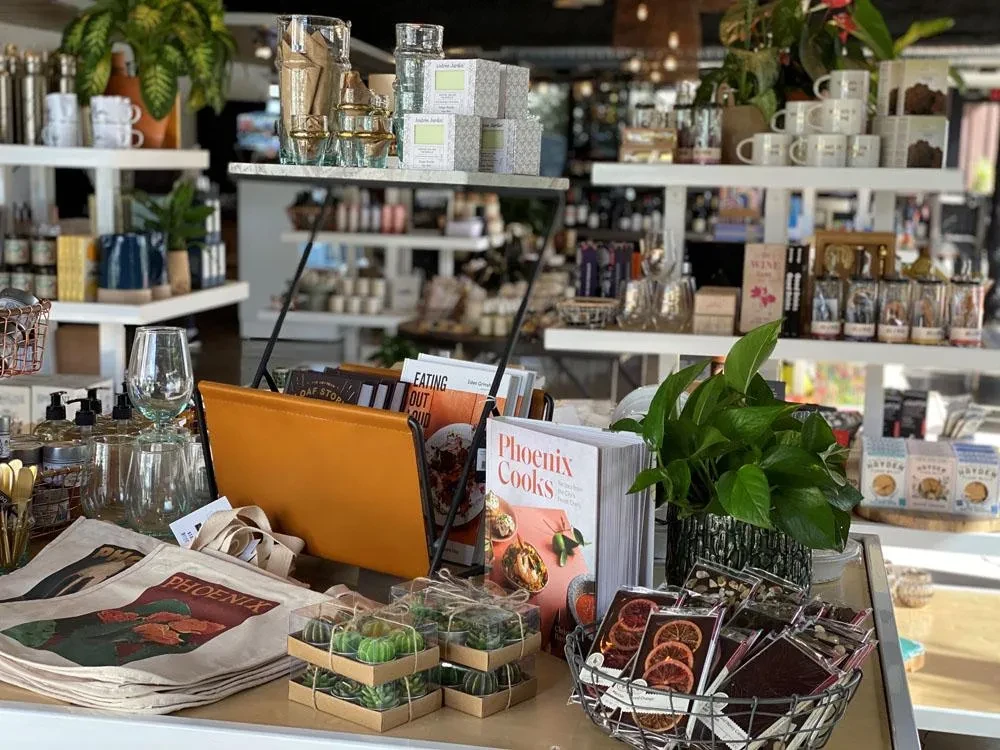 Retail shop display with Phoenix bags, books, and gourmet items.