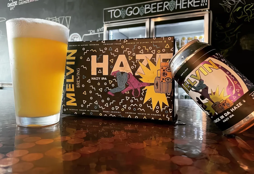 Melvin Brewing Hazy IPA: glass, carton, and can on a bar.