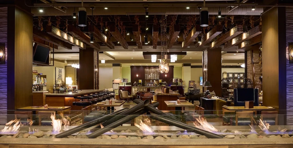 Modern restaurant interior with a glass fireplace, bar, and lounge.
