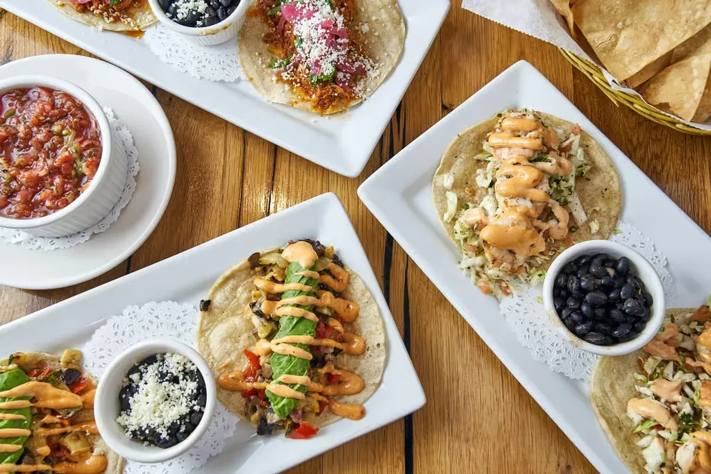 Overhead view of several Mexican tacos with sides and chips.