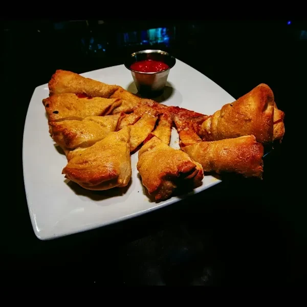 Golden-brown braided pastry with red filling and marinara sauce on a plate.