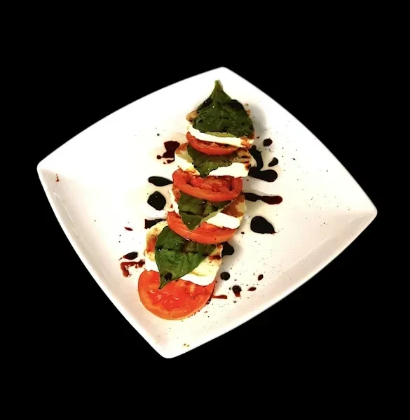 Stacked Caprese salad with tomato, mozzarella, basil, and balsamic glaze.