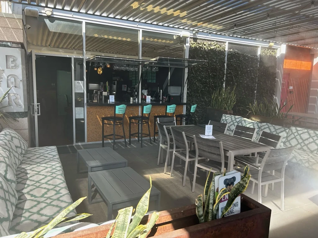 Sunny restaurant patio with modern bar, diverse seating, and lush ivy.