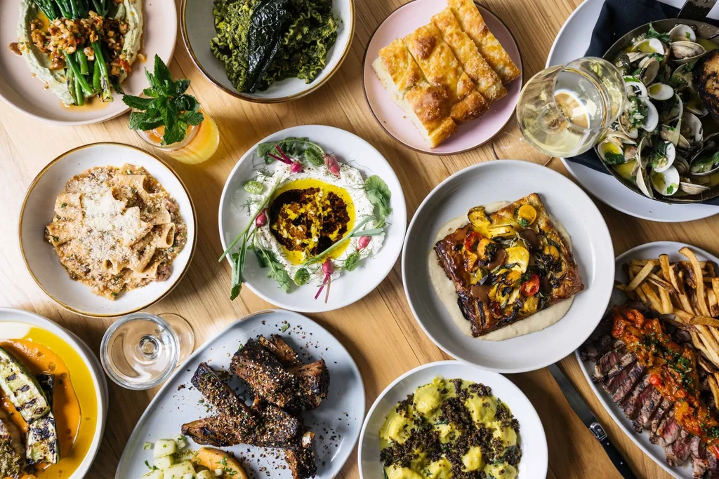 Flat-lay of diverse dishes and drinks on a wooden table.