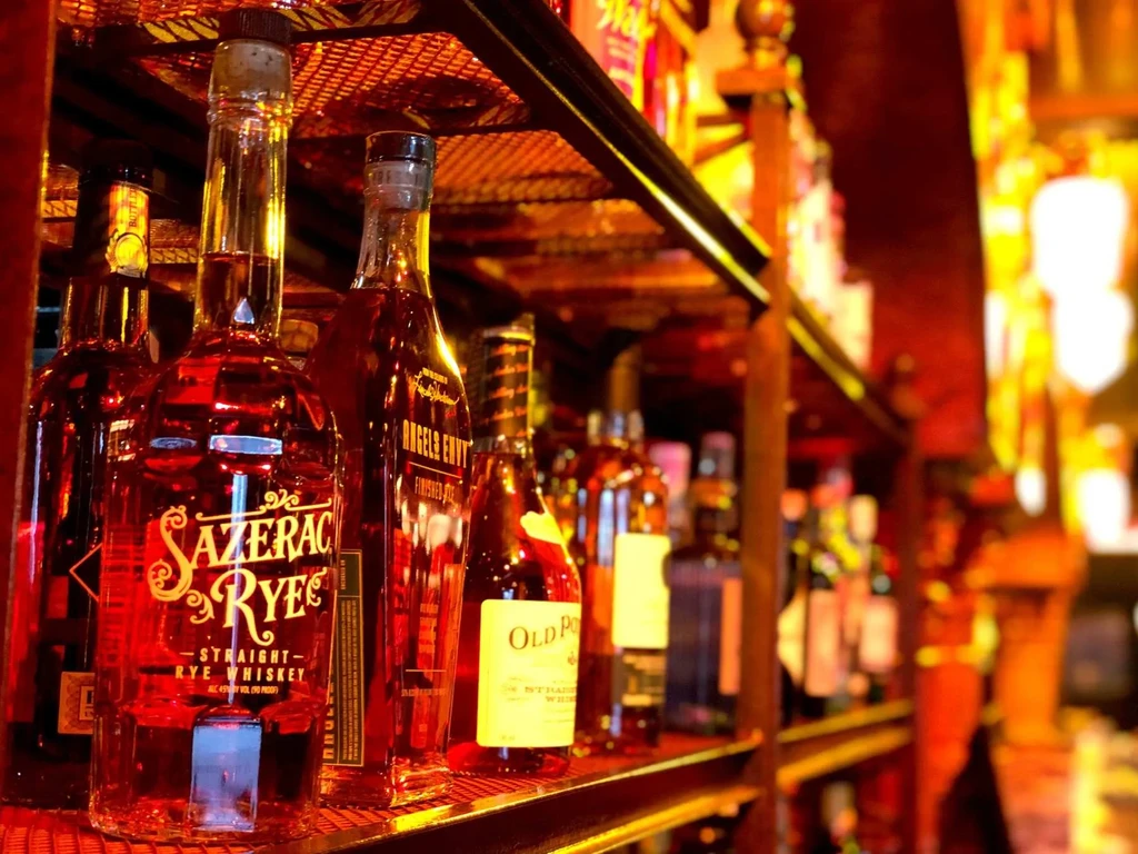Close-up of Sazerac Rye and Angel's Envy whiskey bottles on a shelf.