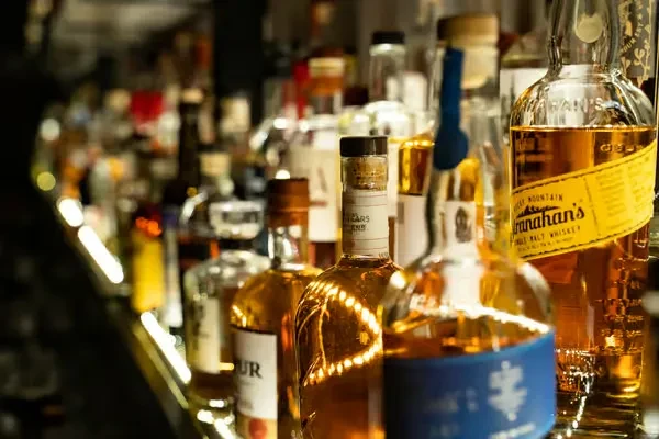 Close-up of a bar shelf displaying various liquor bottles, including Stranahan's whiskey.