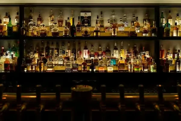 A well-stocked, illuminated back bar with various spirits and beer taps.