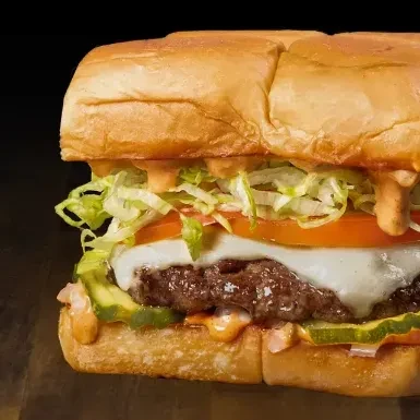Toasted beef sub sandwich with cheese, tomato, lettuce, pickles, sauce.