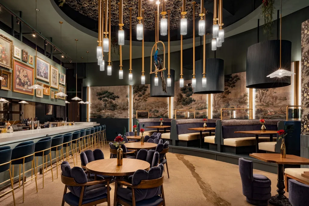 Luxurious restaurant interior with elegant bar, velvet seating, and peacock decor.