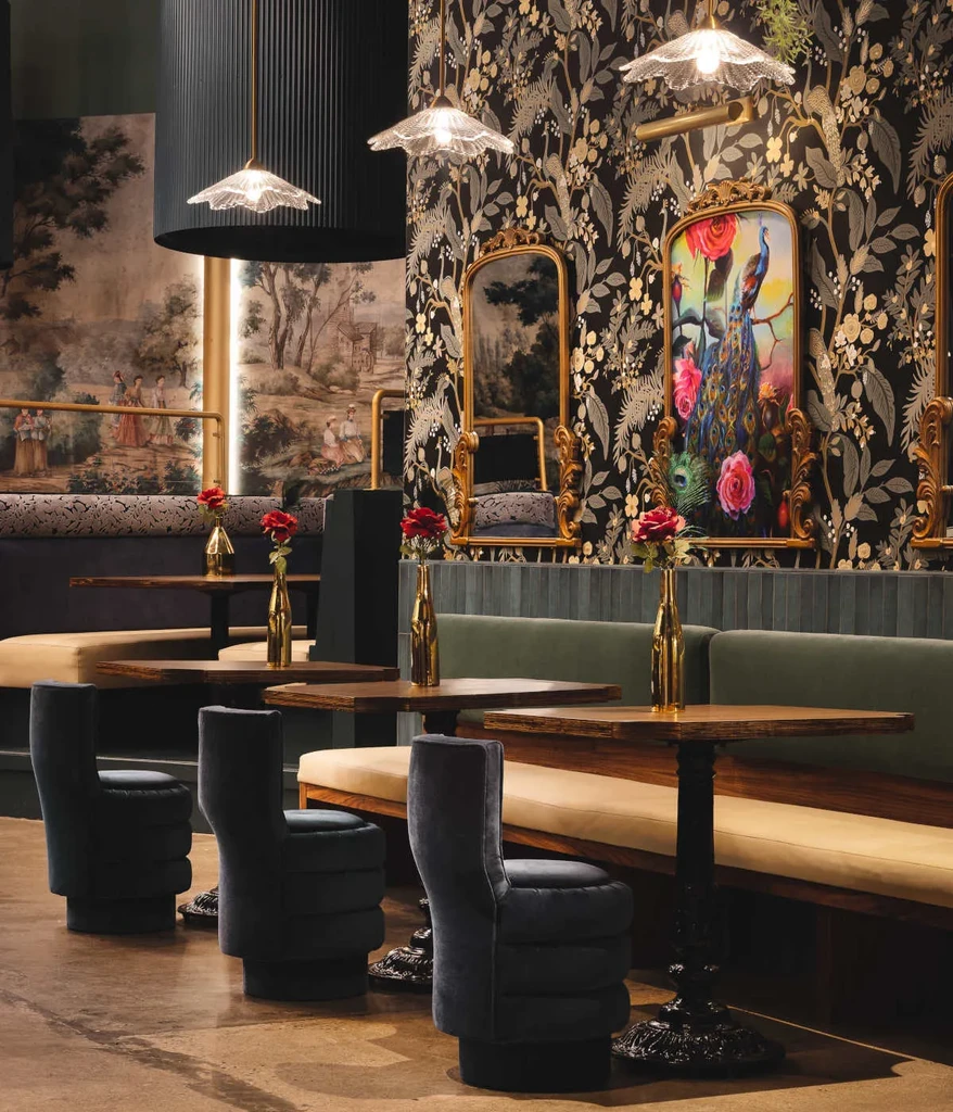 Restaurant interior: gold floral wallpaper, green velvet seating, classical mural.