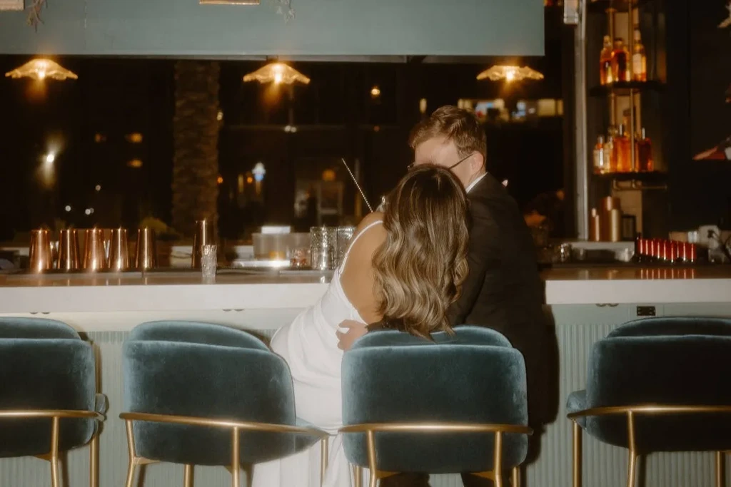 Man and woman leaning closely at a bar counter at night.