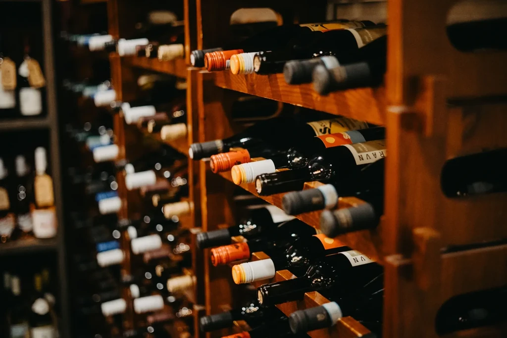 Numerous red wine bottles horizontally displayed on wooden wine rack.