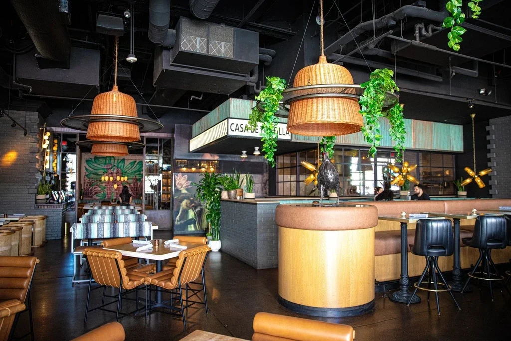 Stylish restaurant interior with industrial ceiling, wicker lamps, and tan leather seats.