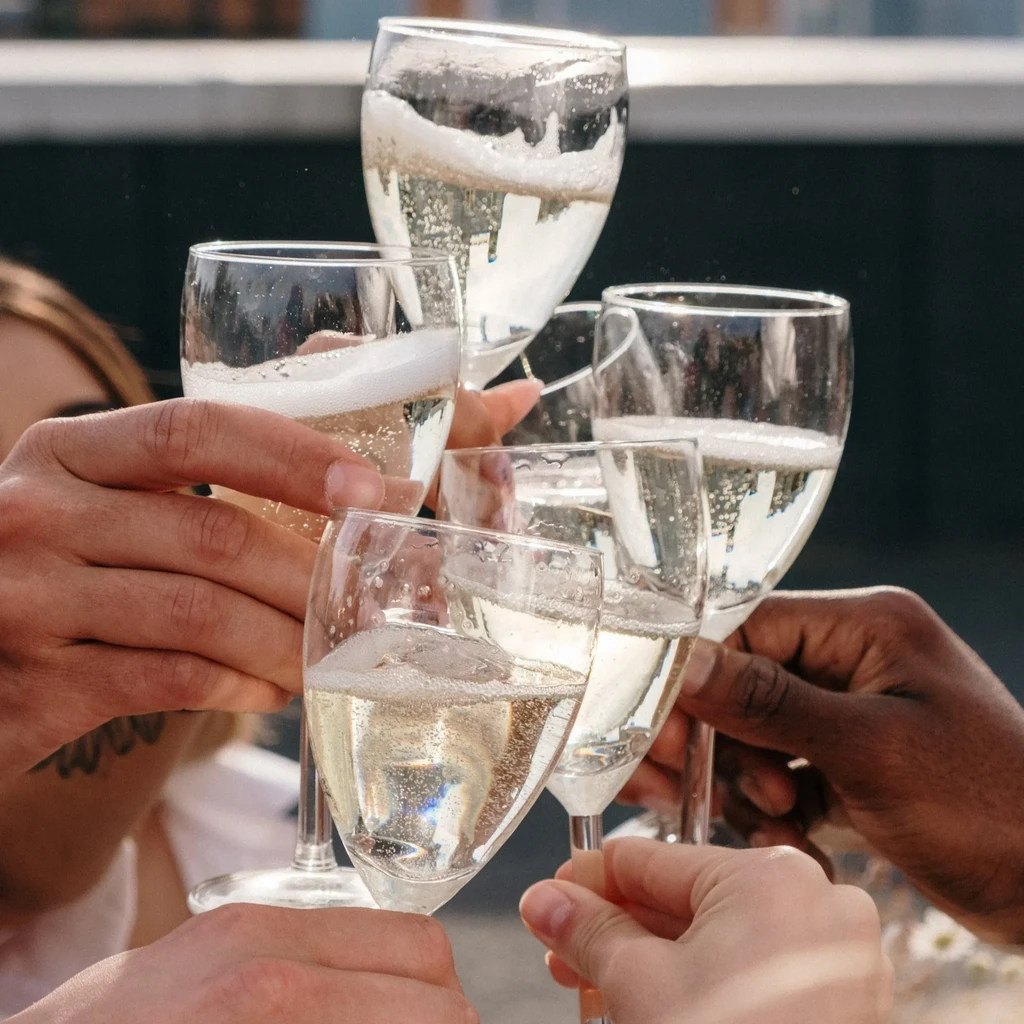 Diverse hands toast with sparkling wine in champagne flutes.