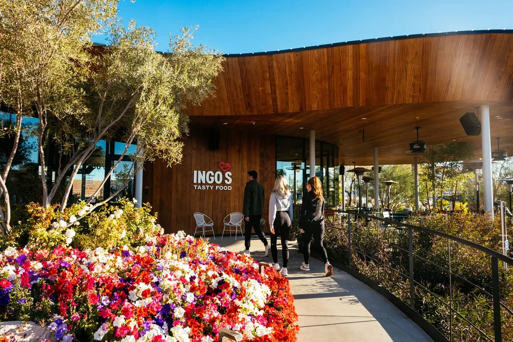 INGO'S TASTY FOOD restaurant exterior: curved wood facade, flowers, people approaching.