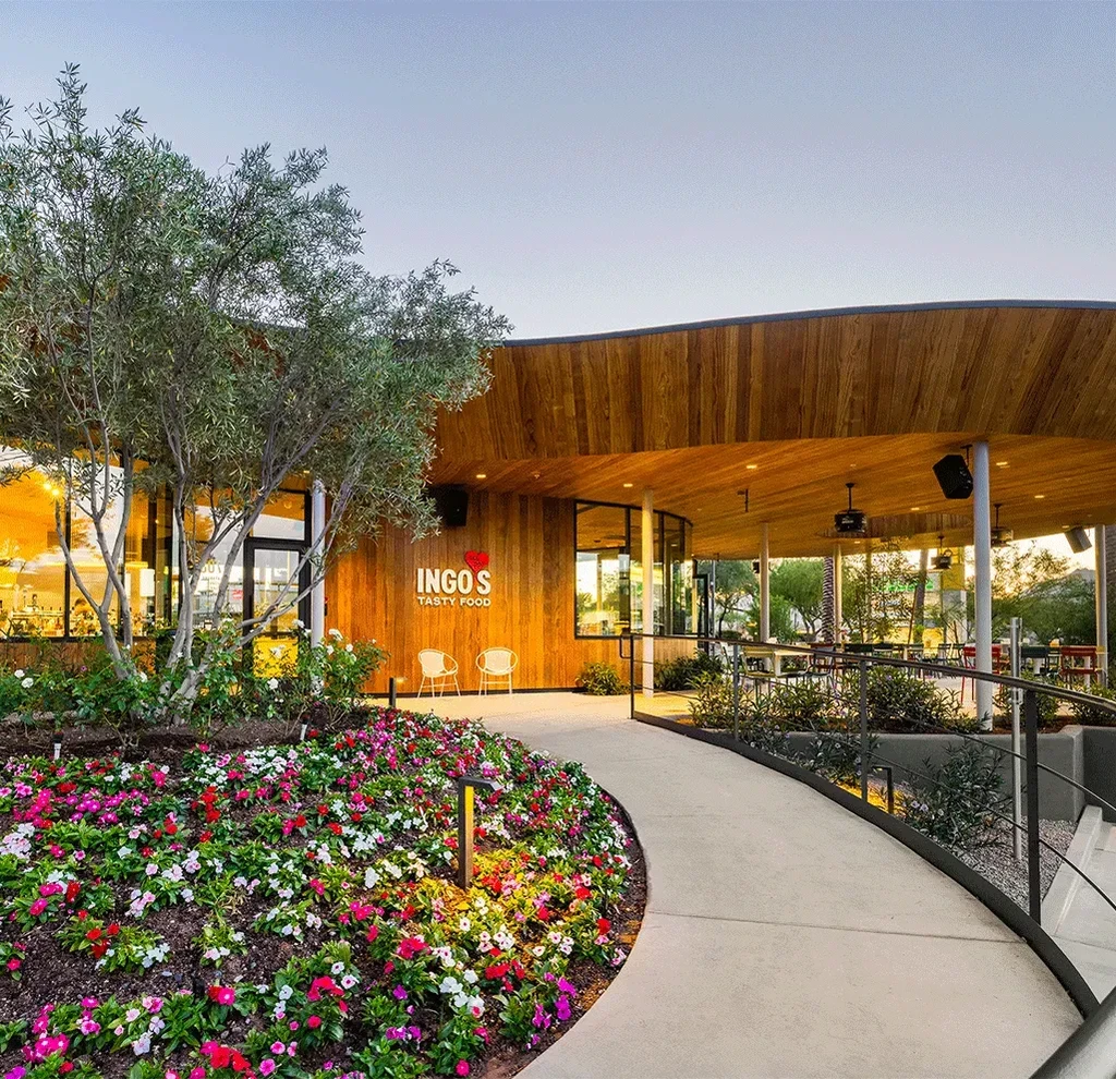 "INGO'S TASTY FOOD" restaurant exterior: curved wood, glass, flowers, and olive tree.