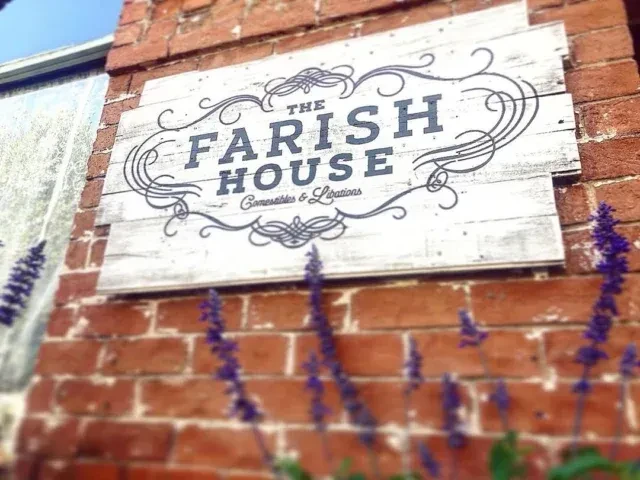 Rustic "THE FARISH HOUSE" sign on a brick wall, with purple flowers.