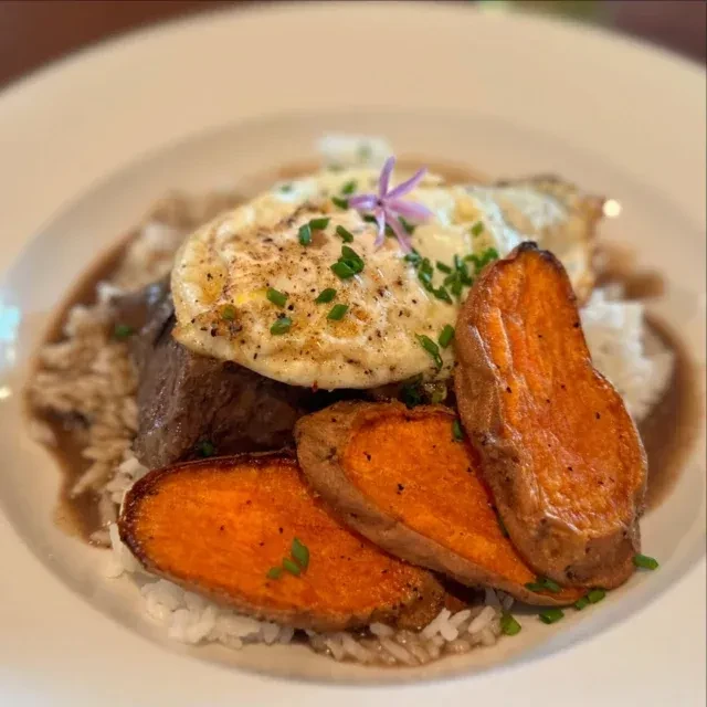 Seared meat, rice, fried egg, gravy, and roasted sweet potato slices.