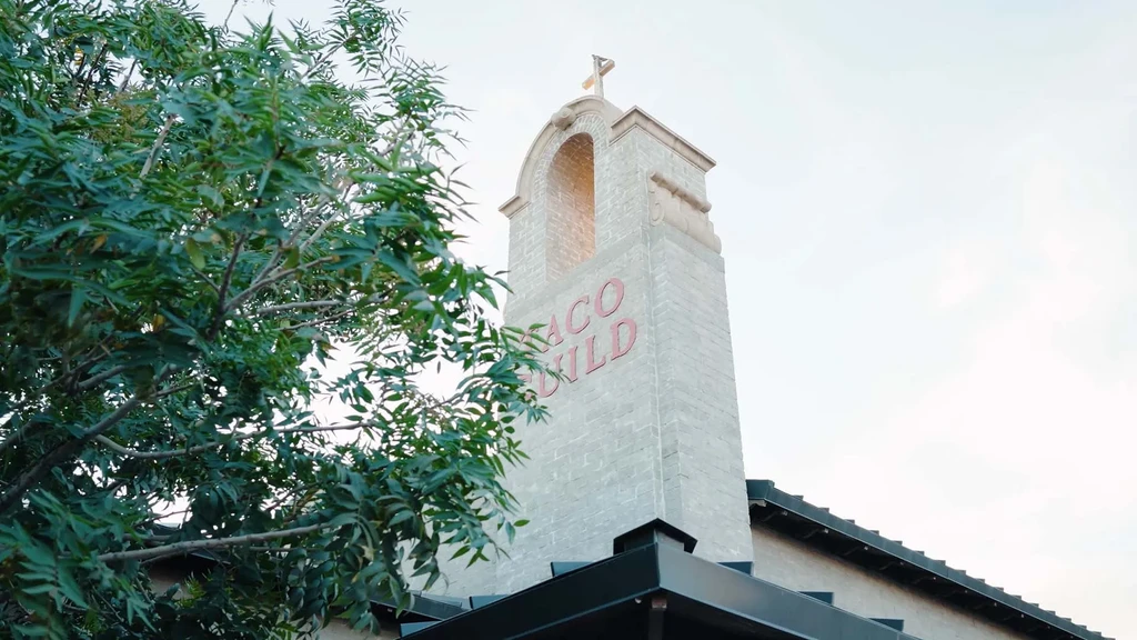 Tall brick tower with "TACO CHILD" sign and a cross ornament.
