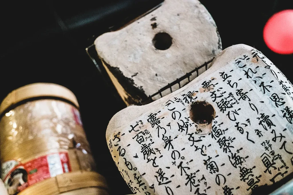 Stacked whitewashed Japanese blocks with calligraphy, circular holes, and dark frames.
