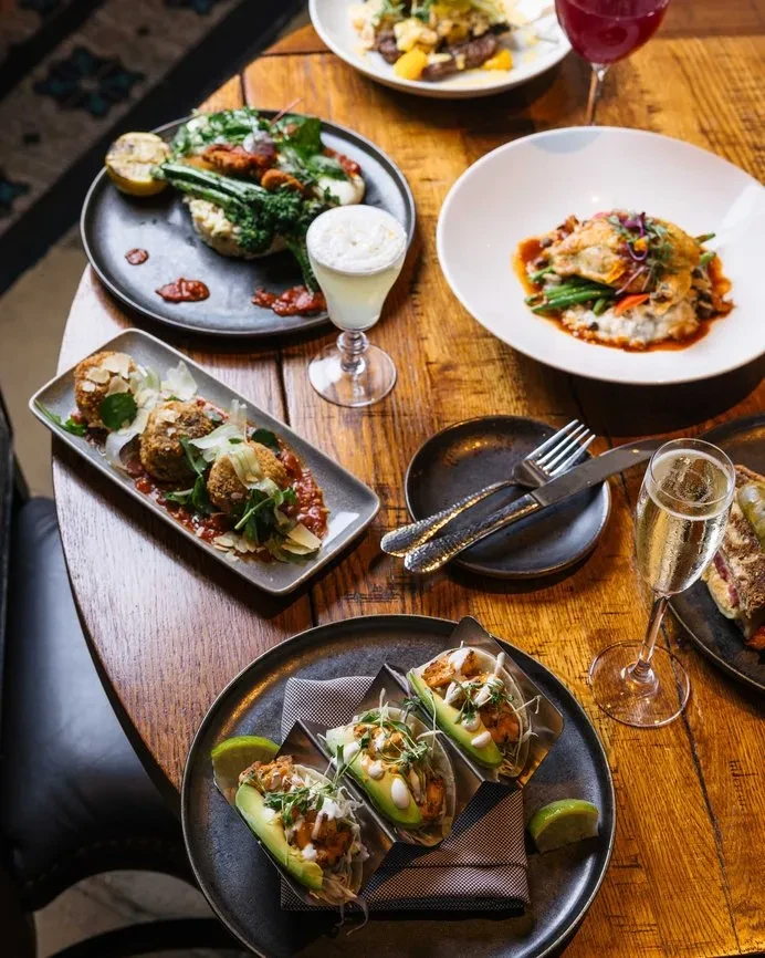 Overhead view of a wooden table with various artfully presented dishes and drinks.