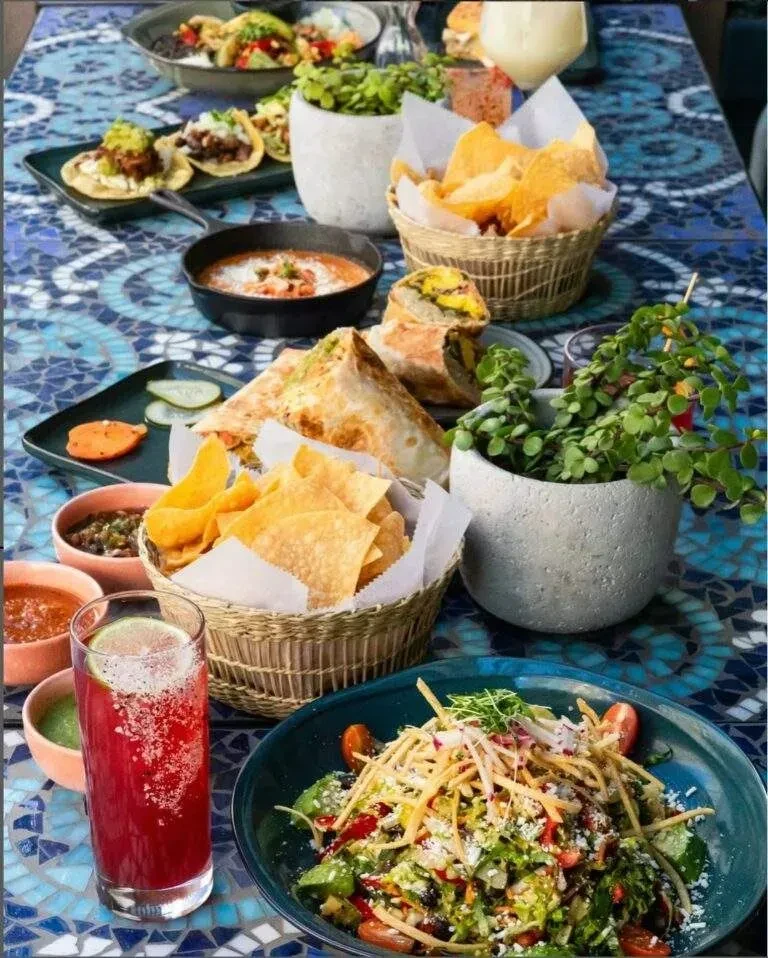 Vibrant overhead view of a mosaic table with Mexican food and drinks.