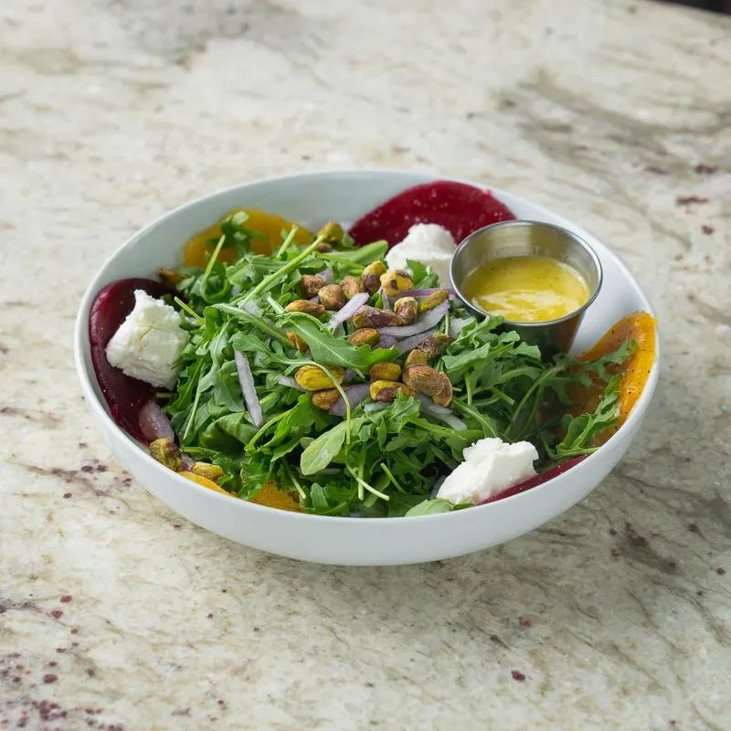 Fresh green salad with pistachios, goat cheese, beets, and vinaigrette.