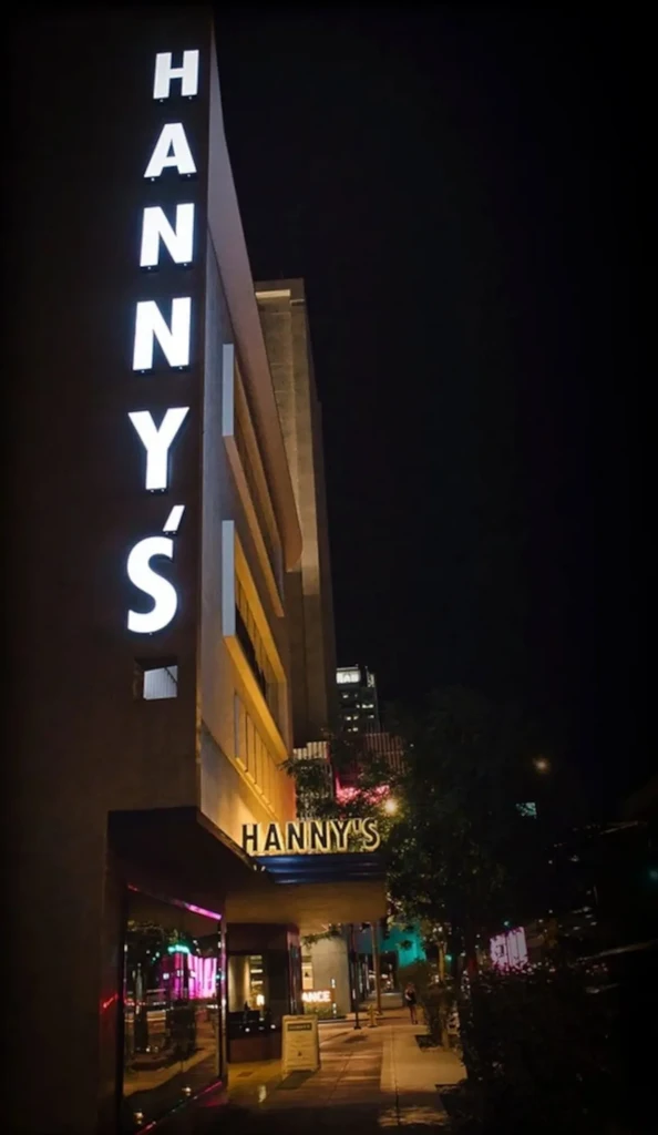 Hanny's building exterior at night, with vertical and horizontal illuminated signs.