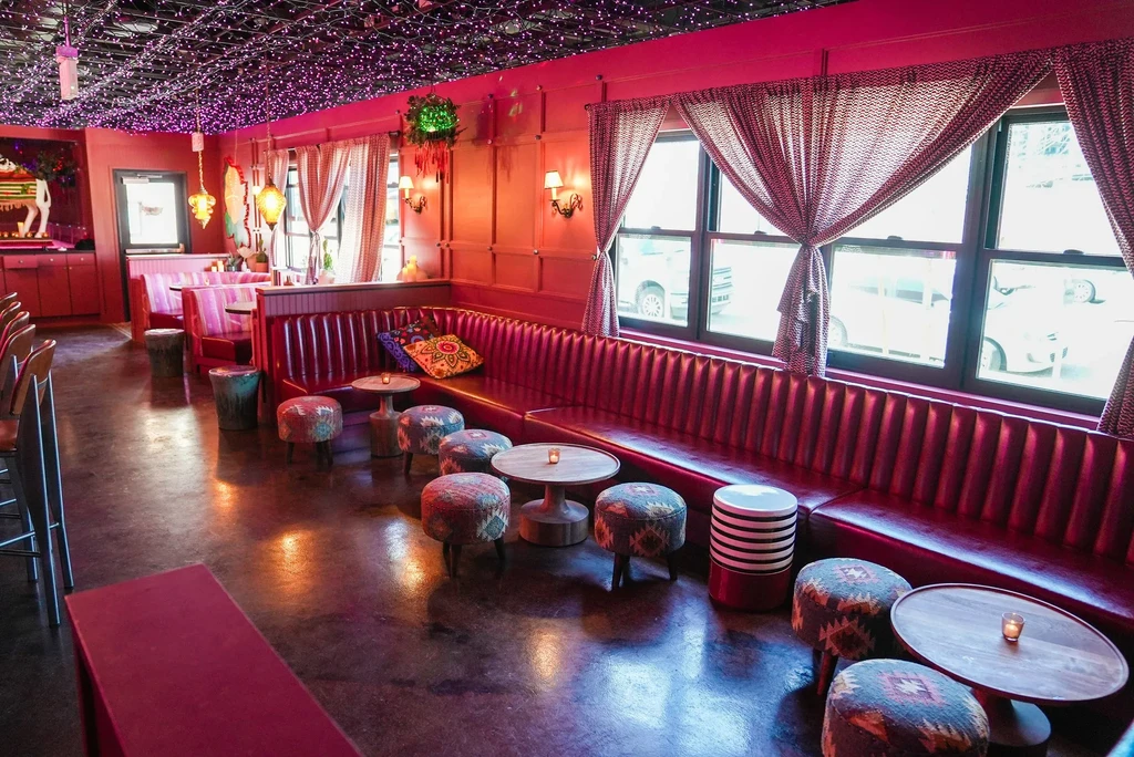 Vibrantly pink restaurant with red booth and sparkling purple string lights.