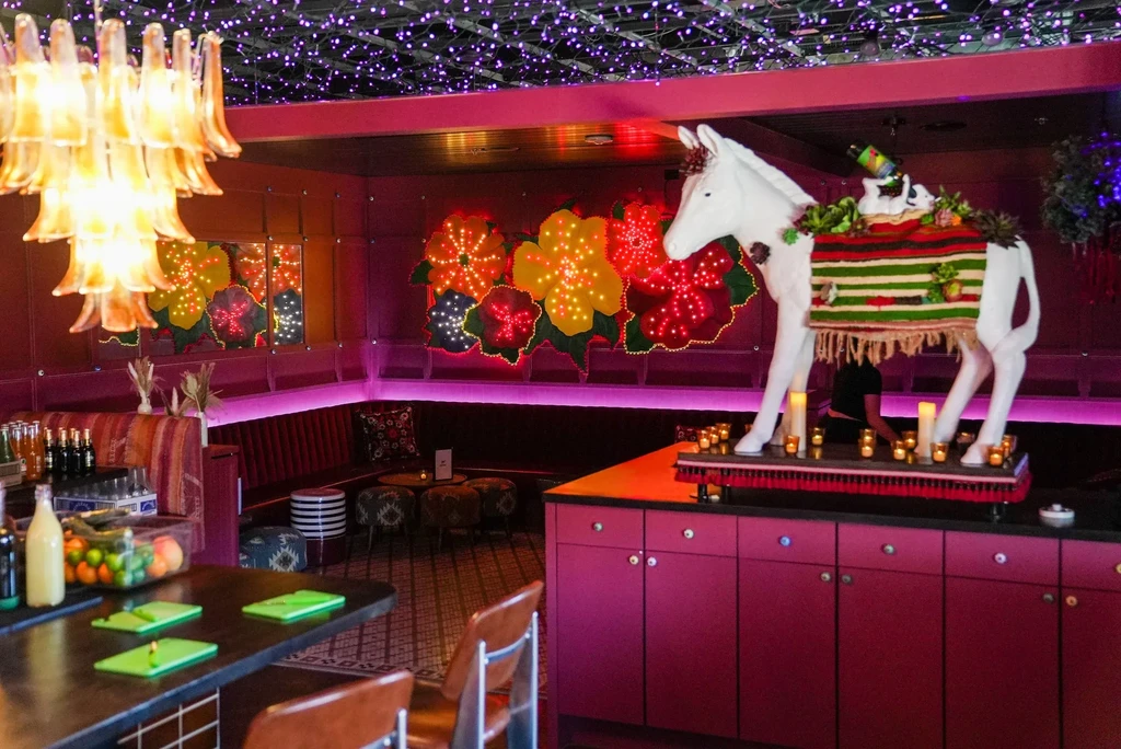 Vibrant restaurant with purple lights, floral art, and a decorated donkey statue.