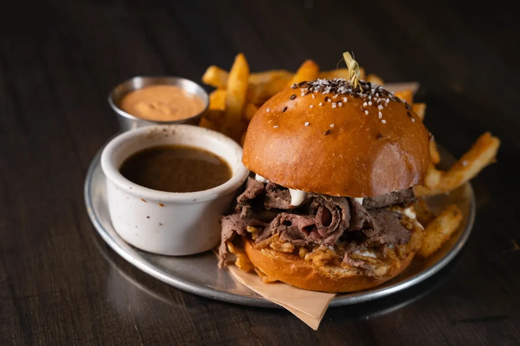 Roast beef sandwich with fries, gravy, and dipping sauce.
