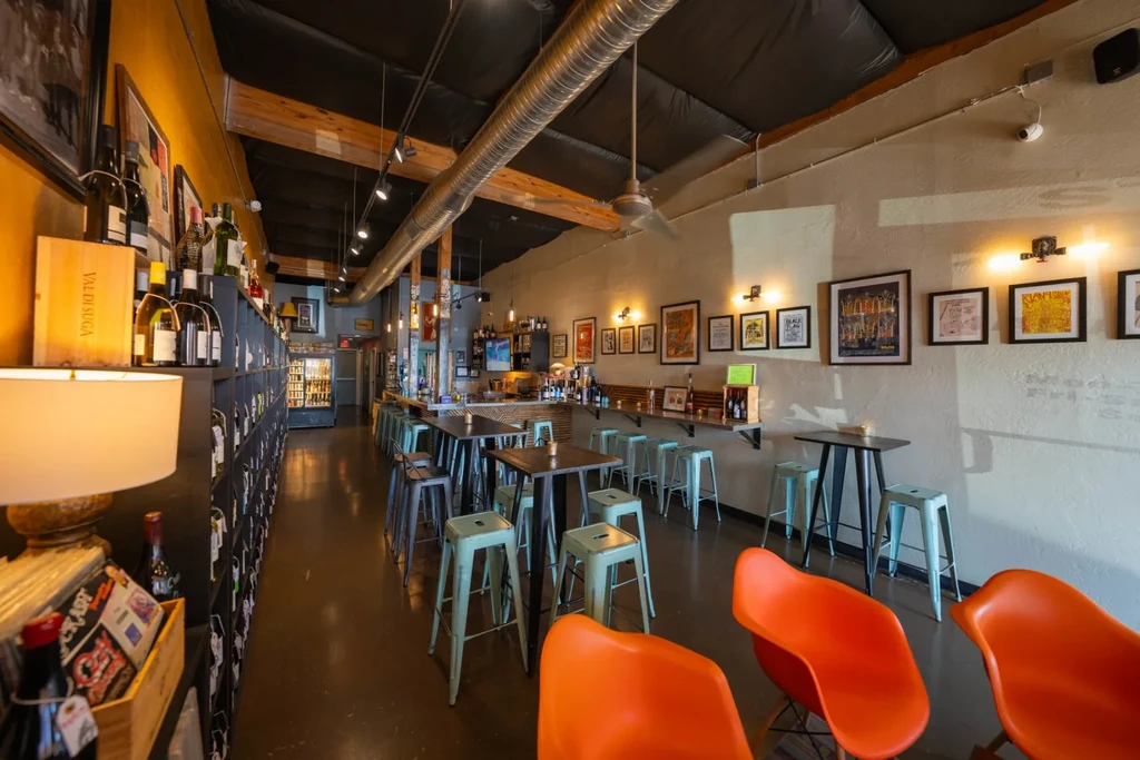 Empty, modern wine bar interior with varied seating and wine display.