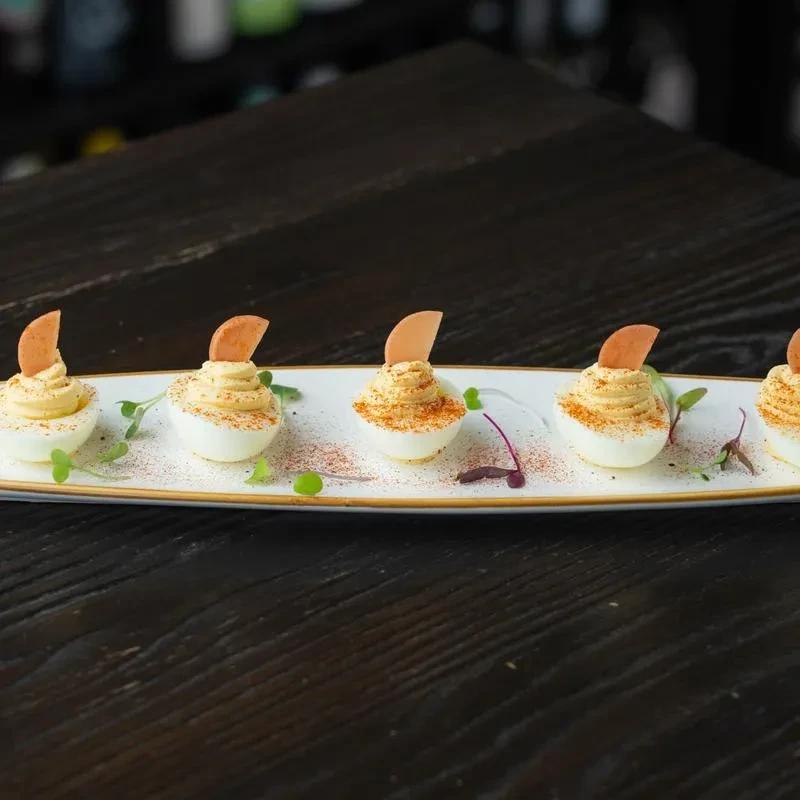 White rectangular plate with six deviled eggs, microgreens, and paprika.