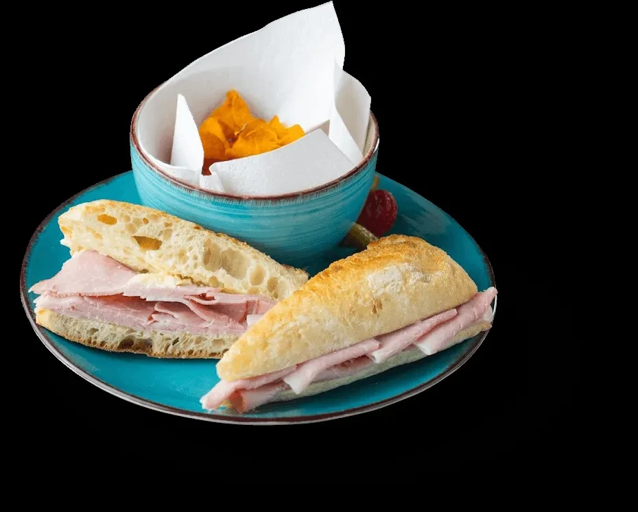 Crispy ham sandwich halves, crinkle chips, and garnishes on a turquoise plate.
