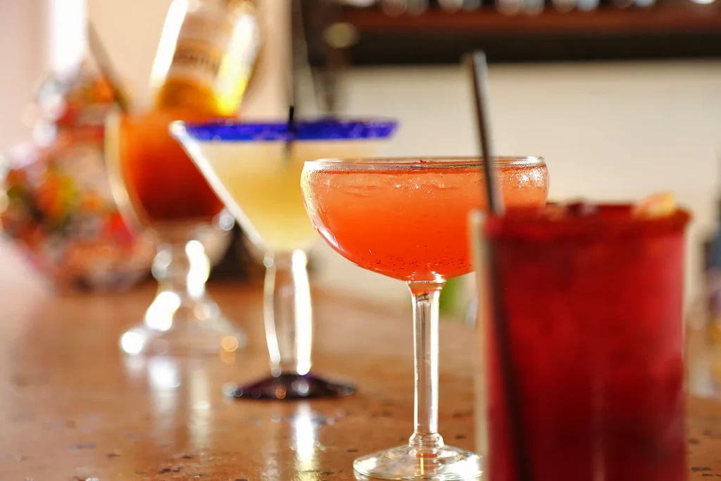 Four colorful, diverse drinks arranged on a reflective bar surface.