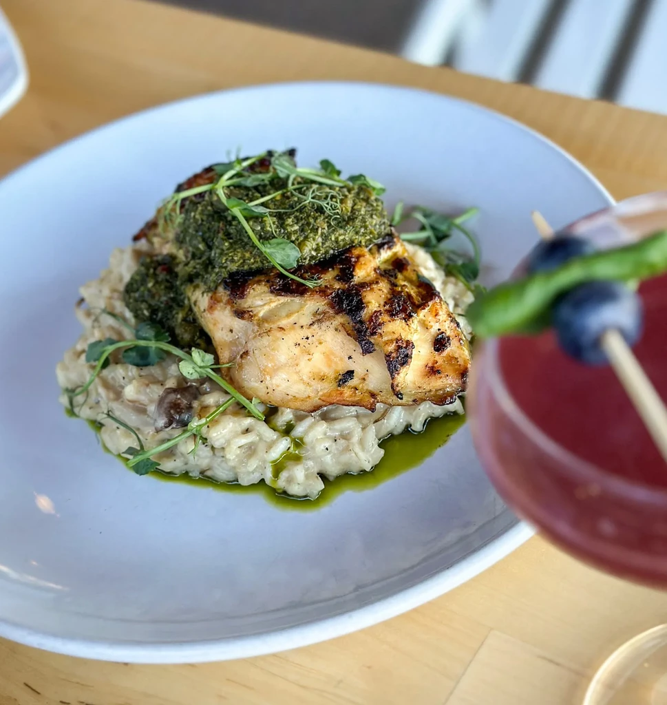 Grilled fish/chicken with pesto, risotto, and a pink cocktail.