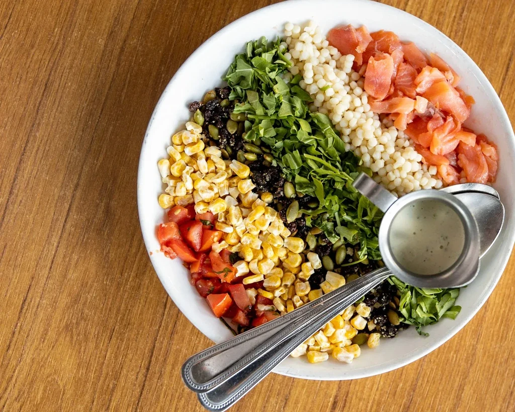 Top-down: Colorful segmented grain bowl with salmon and vegetables.
