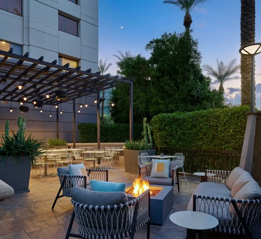 Outdoor patio with lit fire pit, string lights, and dining at dusk.