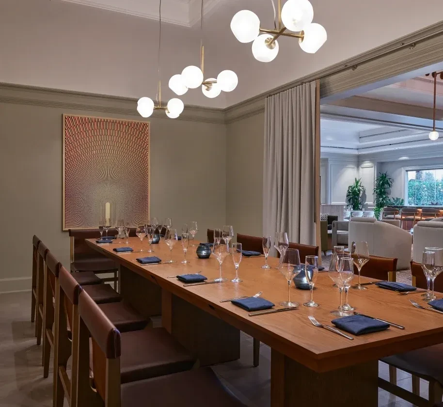 Sophisticated private dining room with long set table and modern chandeliers.