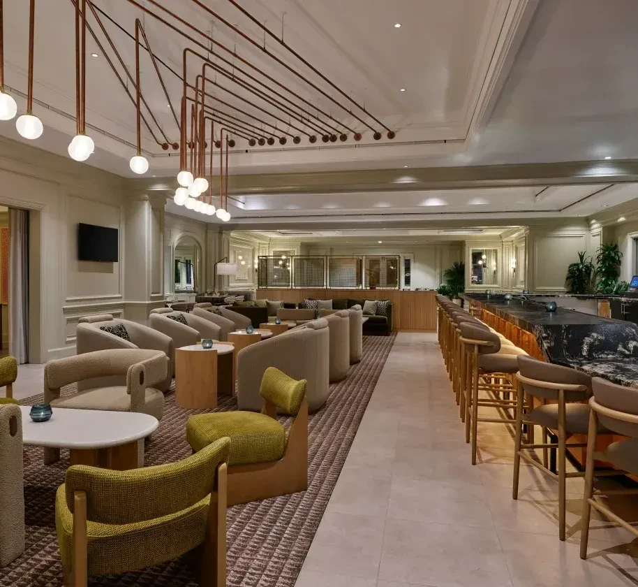Modern restaurant interior with lounge seating, bar, and copper pipe lighting.