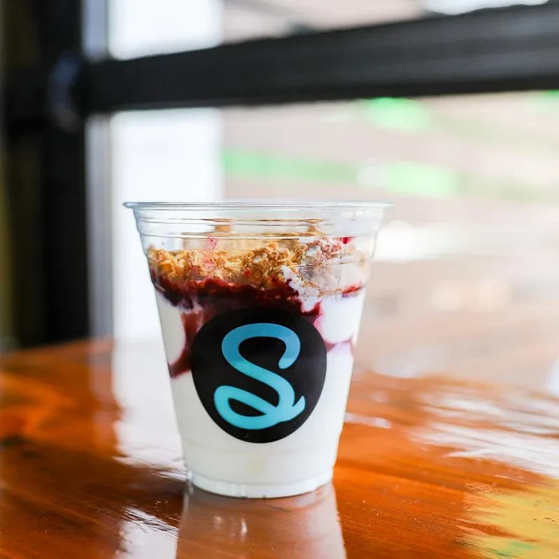 Plastic cup of layered yogurt parfait with fruit, granola, and 'S' logo.