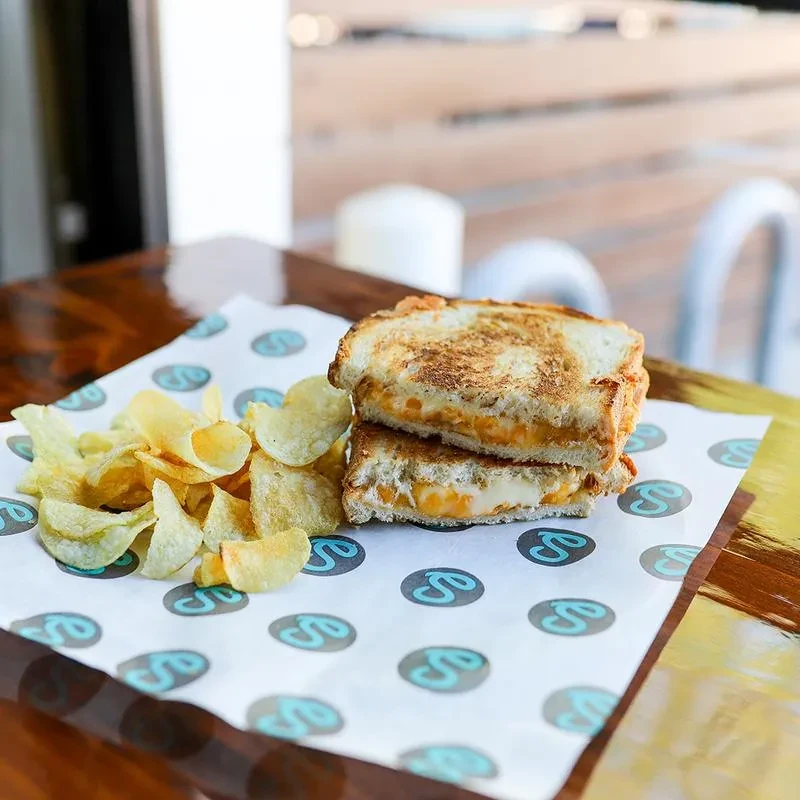Halved grilled cheese and crispy potato chips on a wooden table.