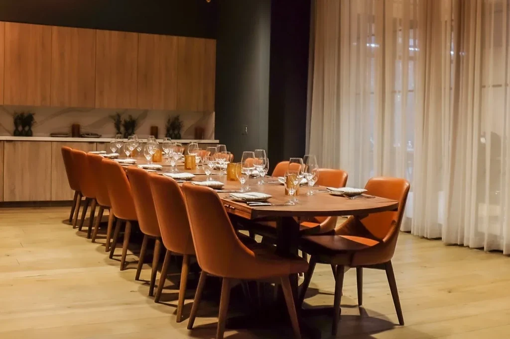 Modern private dining room with long dark table and orange chairs.