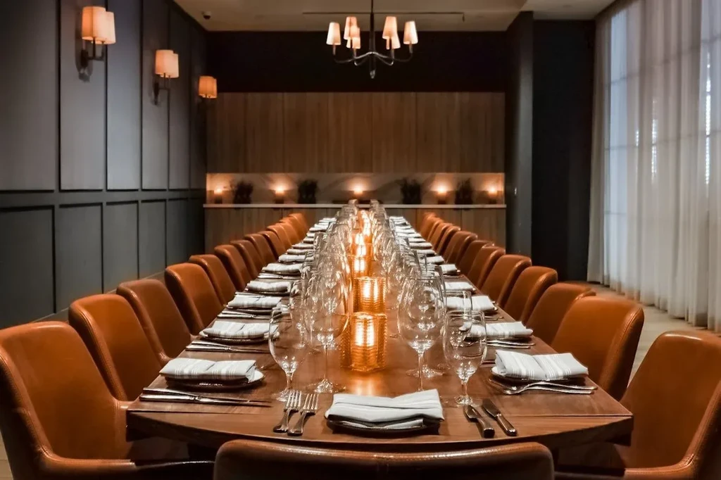 Empty, elegantly set private dining table illuminated by warm candlelight.