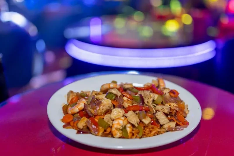 Plate of colorful stir-fry with chicken, shrimp, vegetables, and rice.