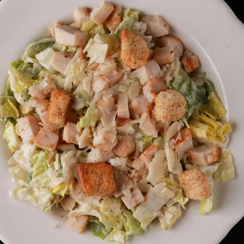 Top-down view of chicken Caesar salad with romaine, croutons, and parmesan.