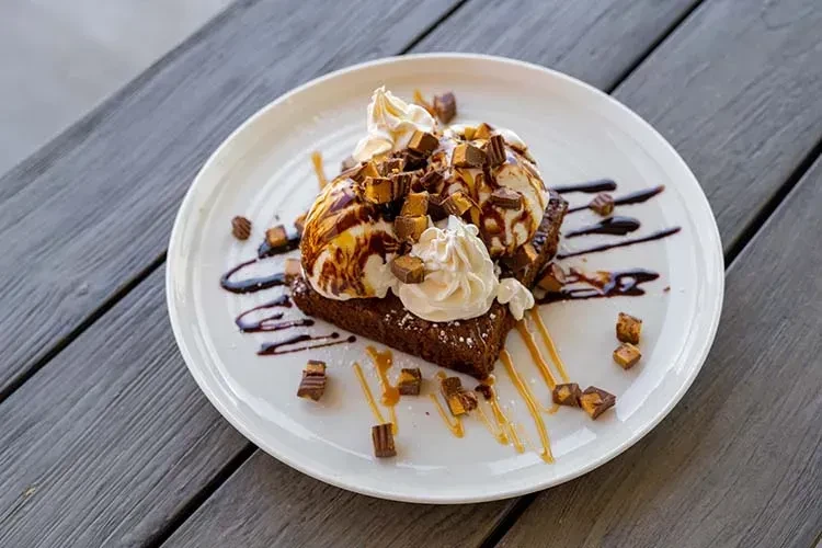 Chocolate brownie with vanilla ice cream, whipped cream, sauces, and chopped candy.