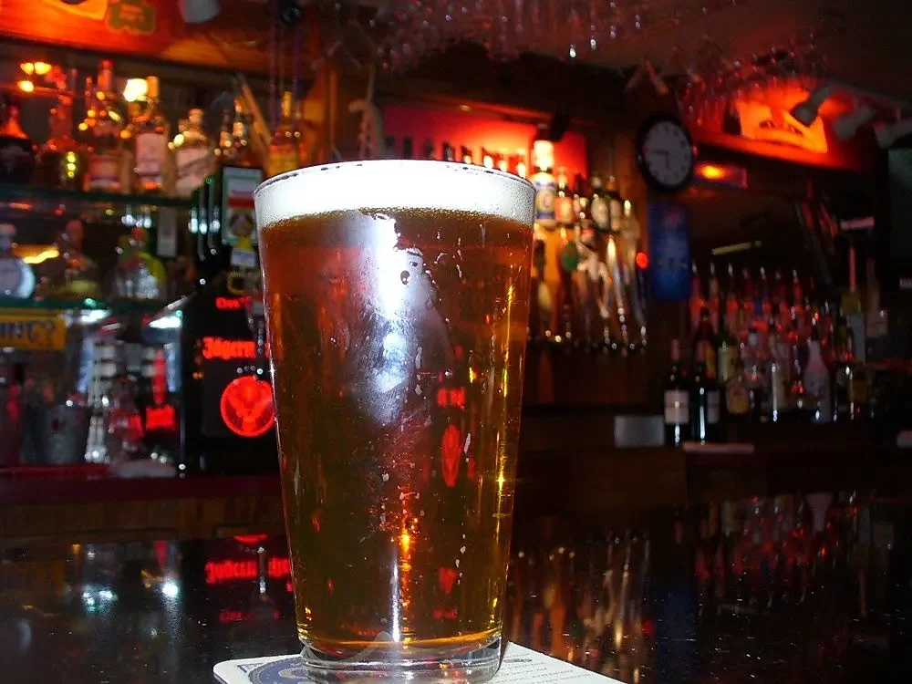 Pint of draft beer on bar counter with taps behind
