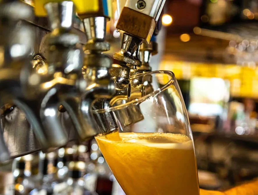 Close-up of golden amber beer pouring from a tap into a glass.