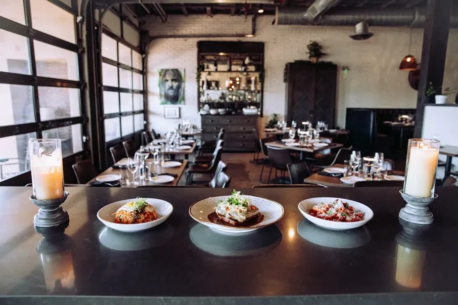 Three artfully plated dishes on a counter in a modern restaurant.